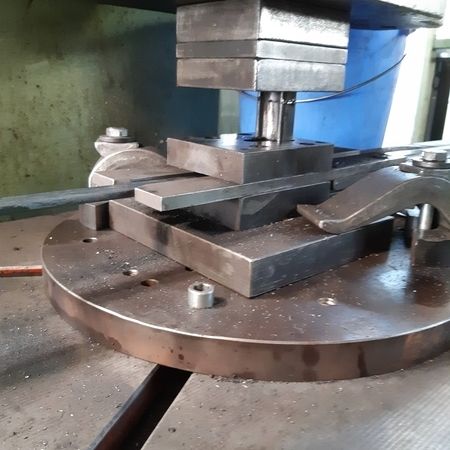 Eine Maschine formt ein Metallstück zu einem neuen Metallteil in einem industriellen Umfeld.